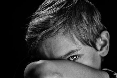 Close-up portrait of boy against black background