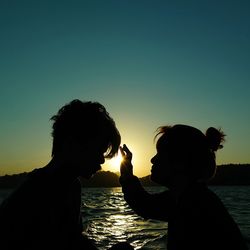 Silhouette of people in water at sunset