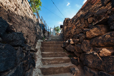 Low angle view of old staircase amidst buildings against sky