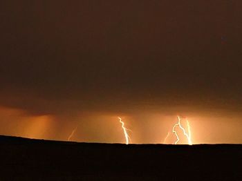 Low angle view of lightning sign against sky at night