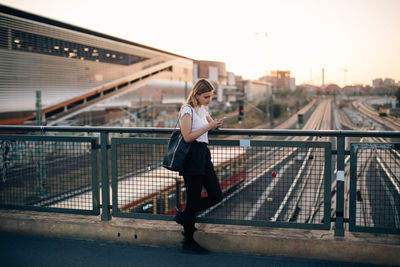 Full length of woman standing on footbridge in city