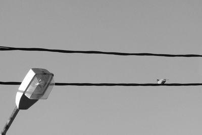 Low angle view of electric lamp hanging against clear sky