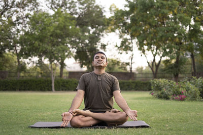 Full length of young man sitting on bench in park