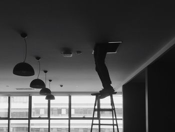 Low section of worker standing on ladder below ceiling