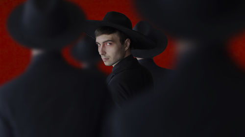 Portrait of young man standing against red background