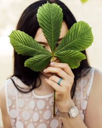 Close-up of woman holding leaves with plant
