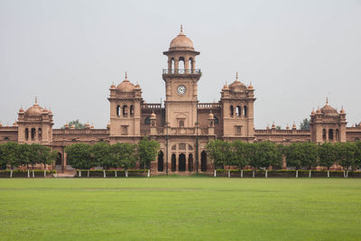 View of historical islamia university peshawar against clear sky and lush carpeted green ground.