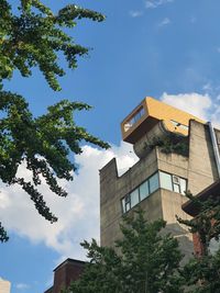 Low angle view of trees and buildings against blue sky