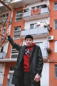 Portrait of young man standing against building