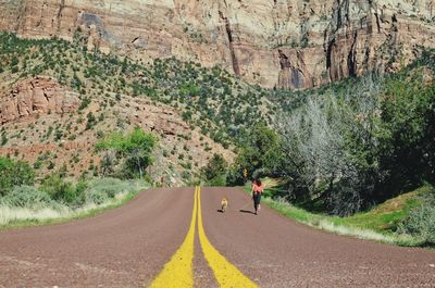 Woman walking with dog on road