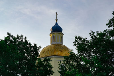 Low angle view of trees and building against sky