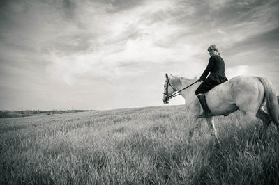 Woman riding horse on grassy field