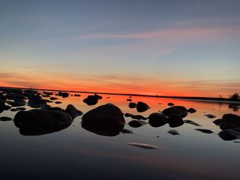 Rocks in lake against sky during sunset