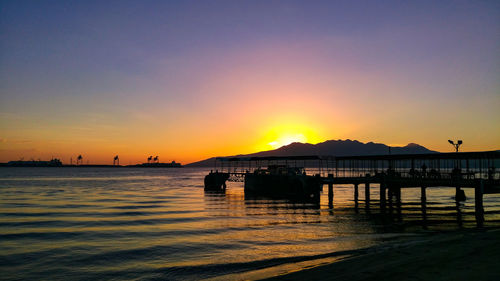Silhouette pier over sea against sky during sunset