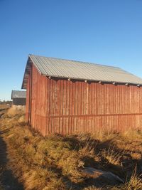 Barn on field against clear blue sky