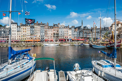 Boats moored at harbor against buildings in city
