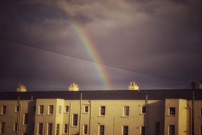 Low angle view of rainbow over buildings against sky