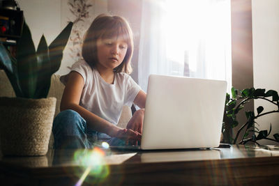 Distance learning. the girl sits at home on the couch and studies using a laptop or makes calls 