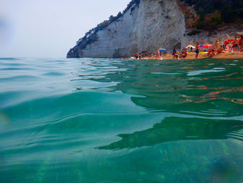 People at sea shore against sky