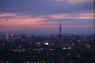 Illuminated cityscape against sky at dusk