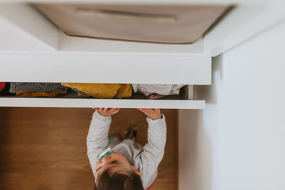 High angle view of baby girl standing by drawer at home