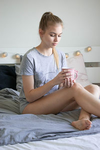 Young woman sitting on bed in bedroom