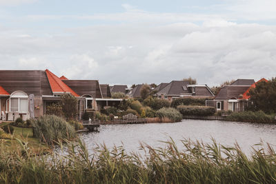 Houses by river and buildings against sky