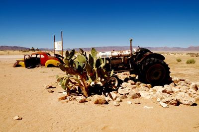 Abandoned car on desert against clear sky