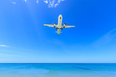 Airplane flying over sea against blue sky