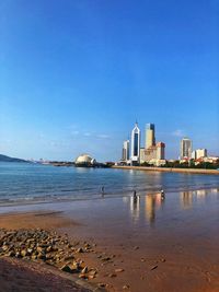 View of sea and buildings against blue sky