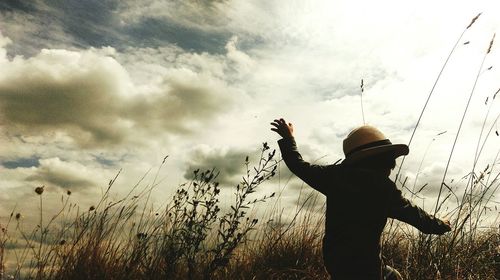 Silhouette of woman standing against cloudy sky at sunset