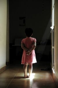 Rear view of girl standing on floor at home