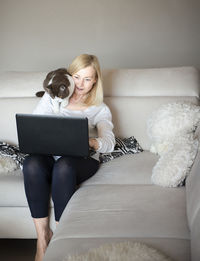 Young woman using mobile phone while sitting on sofa at home