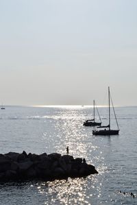 Sailboat on rock in sea against sky