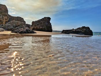 Rock formation on beach against sky