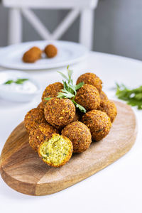 A traditional israeli dish fresh falafel on a wooden board, garnished with a sprig of parsley.