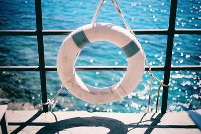 High angle view of white inflatable ring hanging from railing on pier against sea