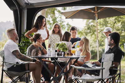 Friends with children relaxing under garden gazebo