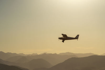 Low angle view of silhouette airplane flying against sky during sunset