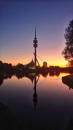Silhouette tower by lake against sky during sunset