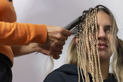 A stylist mother getting her teenage daughter senegalese braids in her home. 