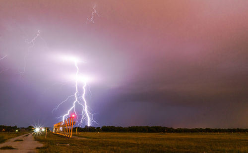 Scenic view of lightning over field against dramatic sky
