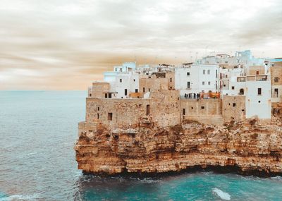 Buildings on beach against cloudy sky