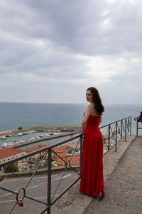 Portrait of woman standing by railing against sea and sky