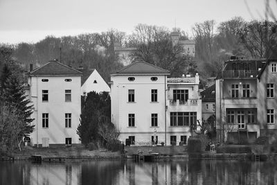 Buildings by lake against sky