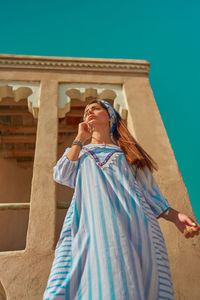 Young woman looking at camera against built structure