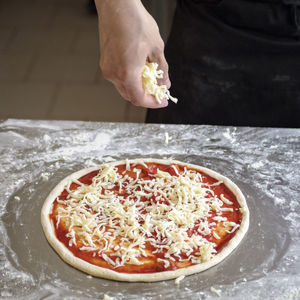 Food cooking, culinary and people concept - cook or baker hand with pizza on peel at pizzeria