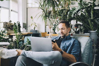 Young man using mobile phone while sitting on chair