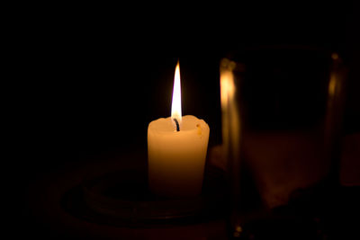 Close-up of lit candle in darkroom