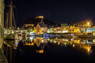 Boats moored at harbor against sky at night